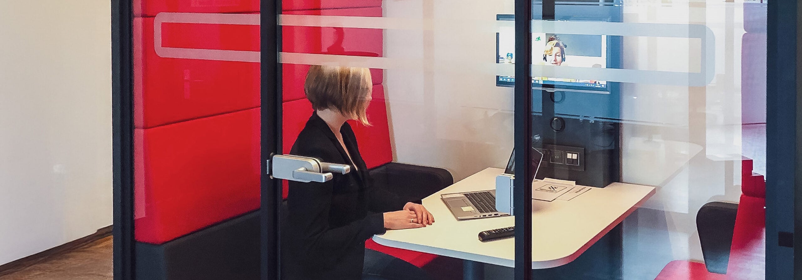 Frau im Beratungsgespräch im Corporate Pension Partner Büro, hinter Glas.