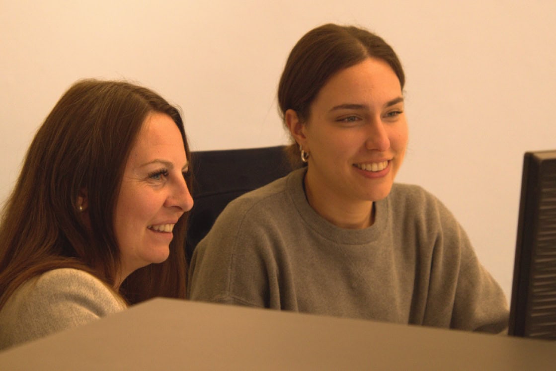 Zwei Frauen arbeiten gemeinsam an einem Computer im Büro.